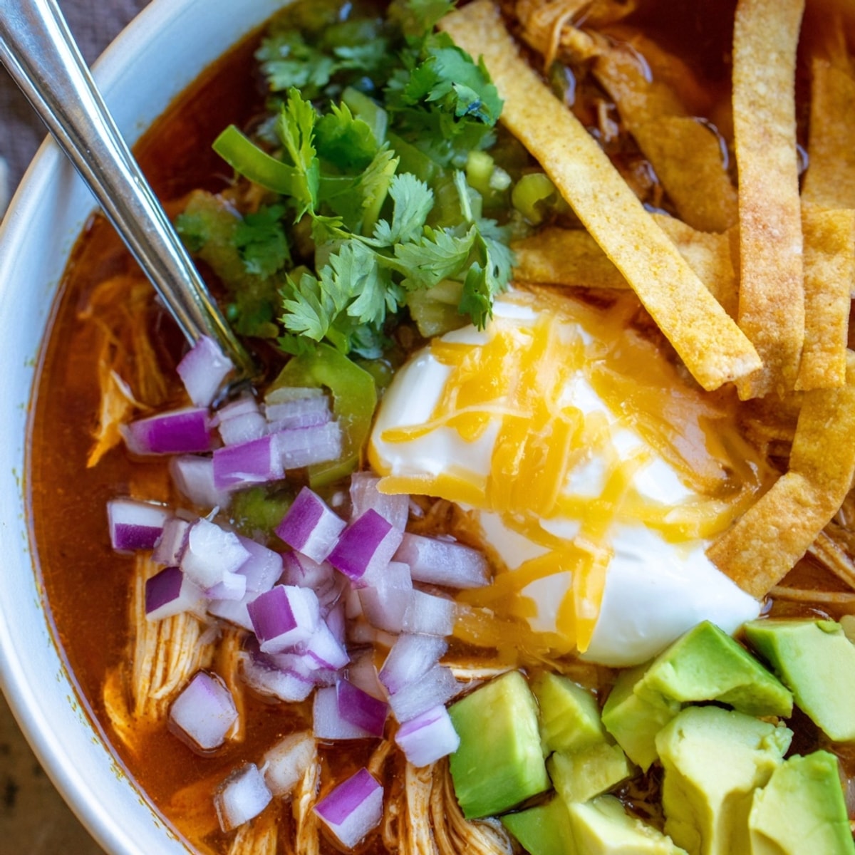 Close-up shot of vibrant Tortilla Soup, showcasing shredded chicken and colorful toppings.