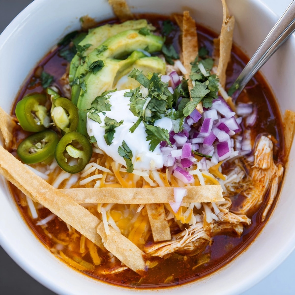 Comforting Tortilla Soup recipe: warm broth, tender chicken, finished with cool sour cream.