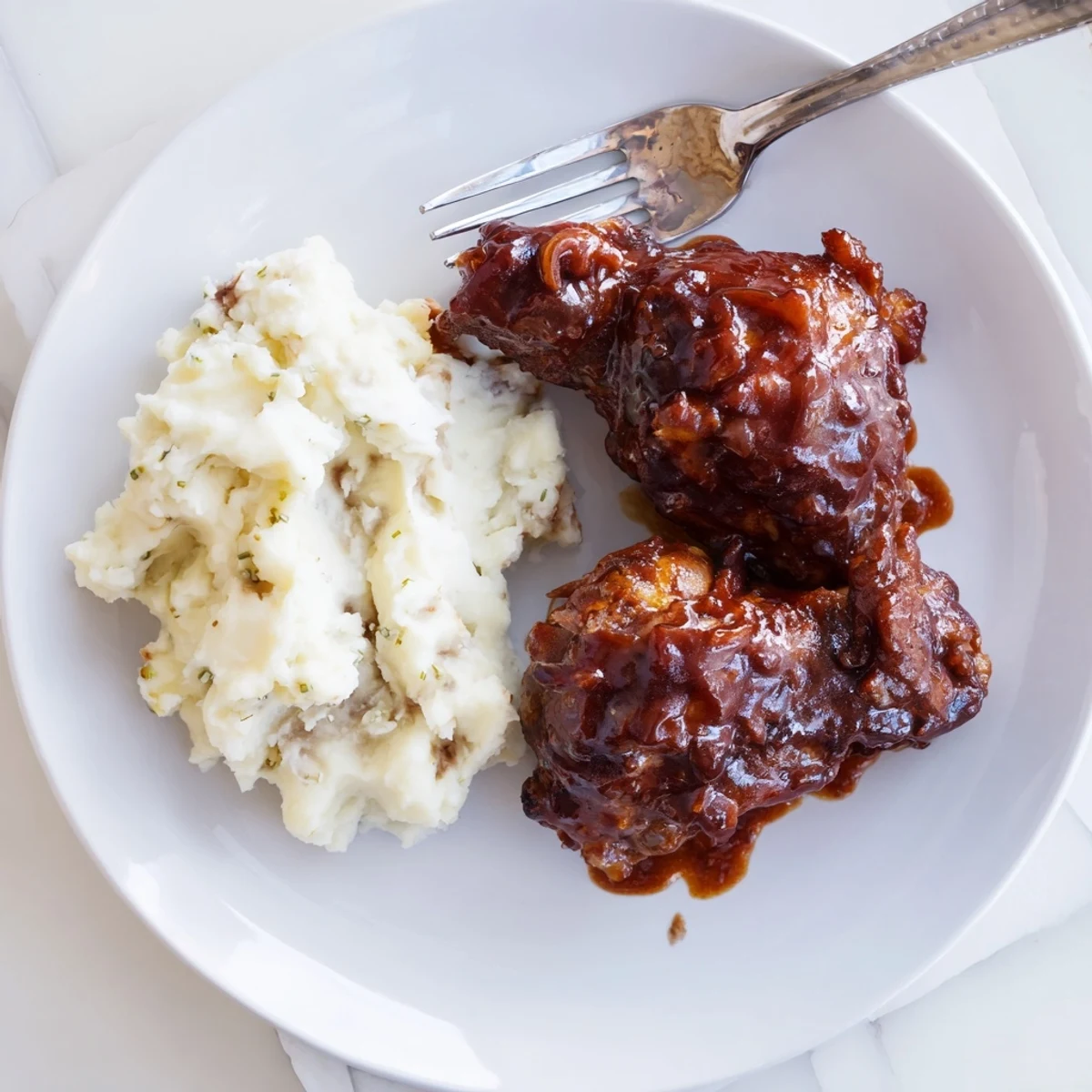 Flavorful honey BBQ chicken thighs alongside velvety garlic mashed potatoes for dinner.