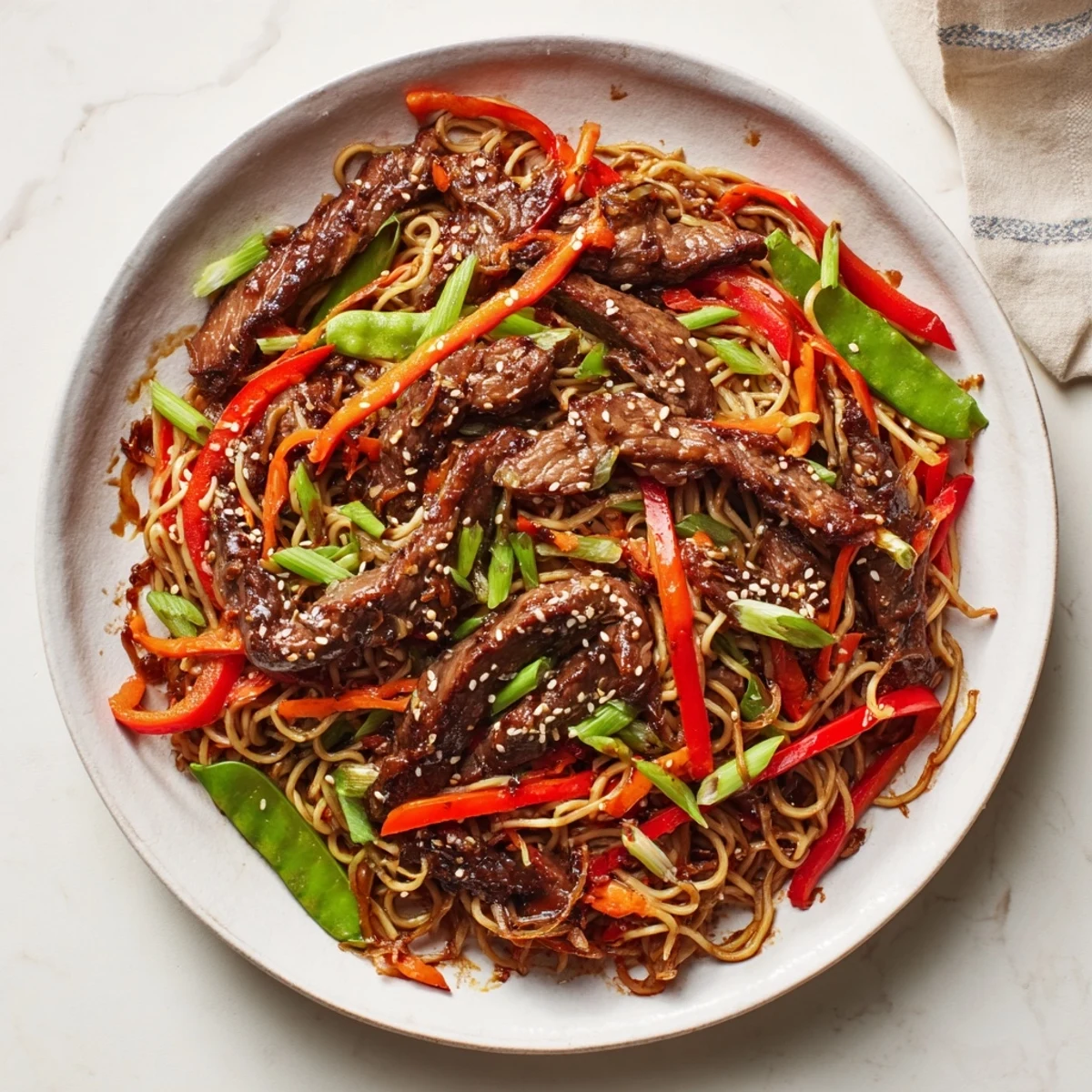 Steaming Teriyaki Beef & Noodle Bowl with glistening noodles and savory, sweet teriyaki sauce, garnished with sesame seeds.