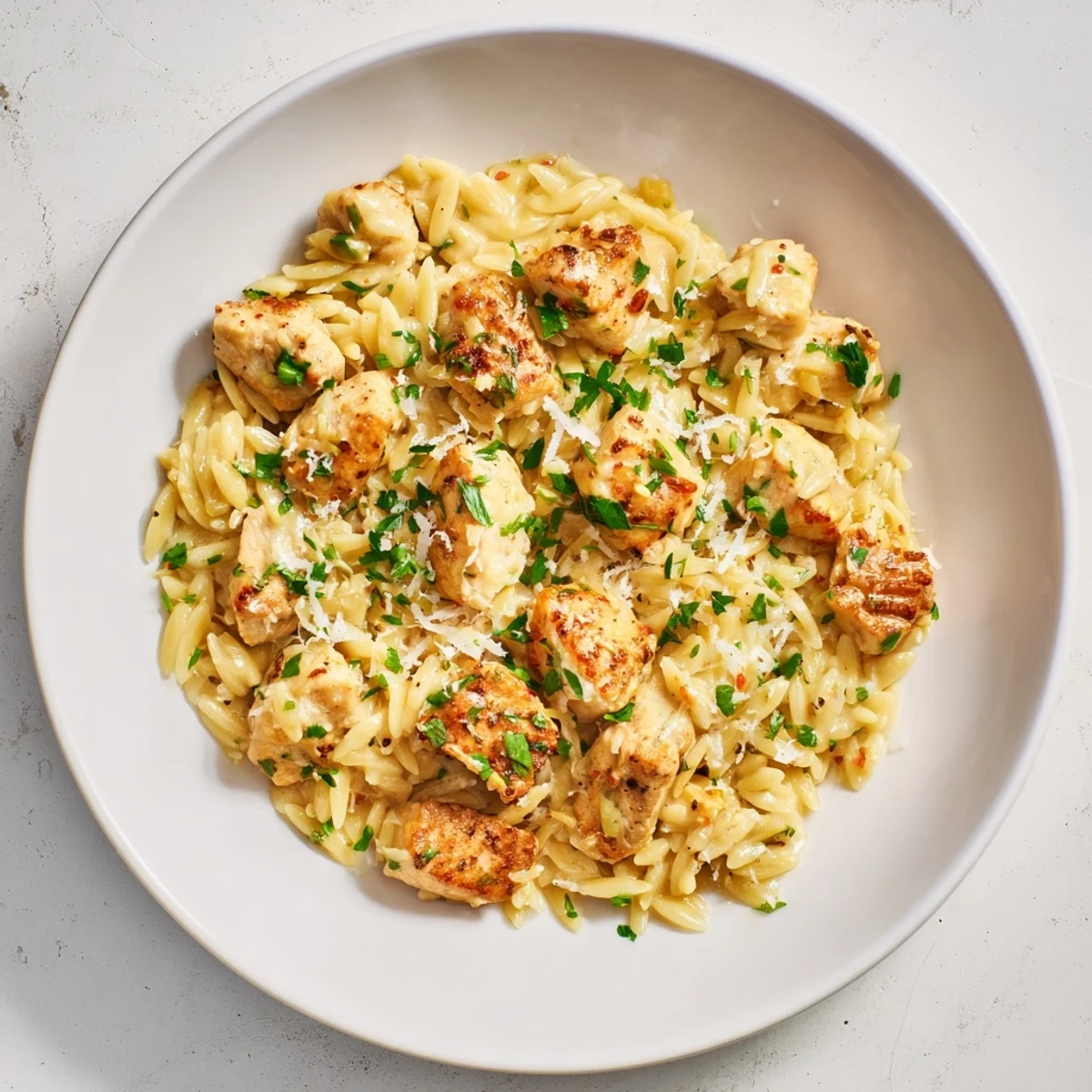 Imagine a steaming bowl of one-pot Cajun Chicken Alfredo Orzo, garnished with fresh parsley and ready to eat.