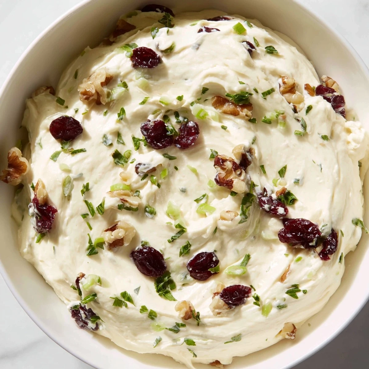 Tangy Lightened Holiday Cream Cheese Dip, garnished with fresh herbs and nuts, perfect as a holiday appetizer.