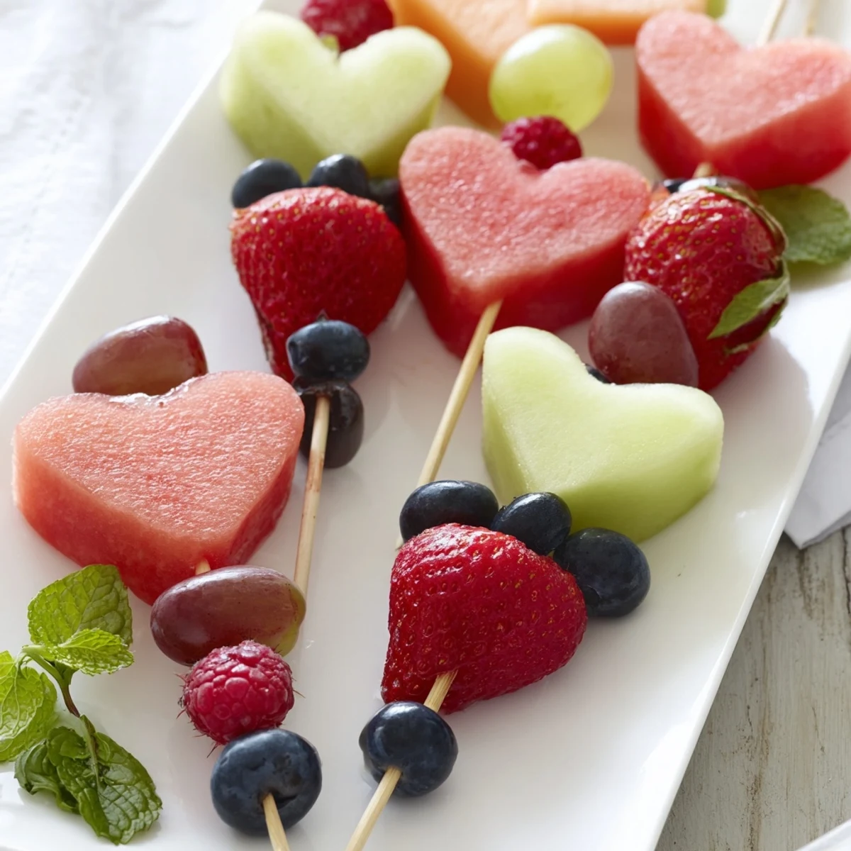 Colorful Berry Good Heart Fruit Skewers, a delightful party snack, are overflowing with fresh, sweet flavors.
