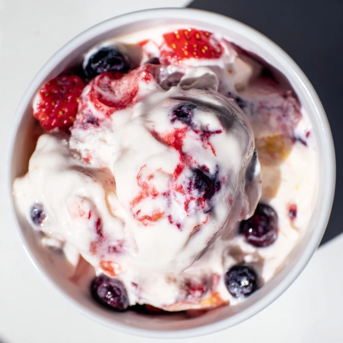 A close-up of creamy cottage cheese ice cream swirled with frozen berries, a delicious, healthy dessert.