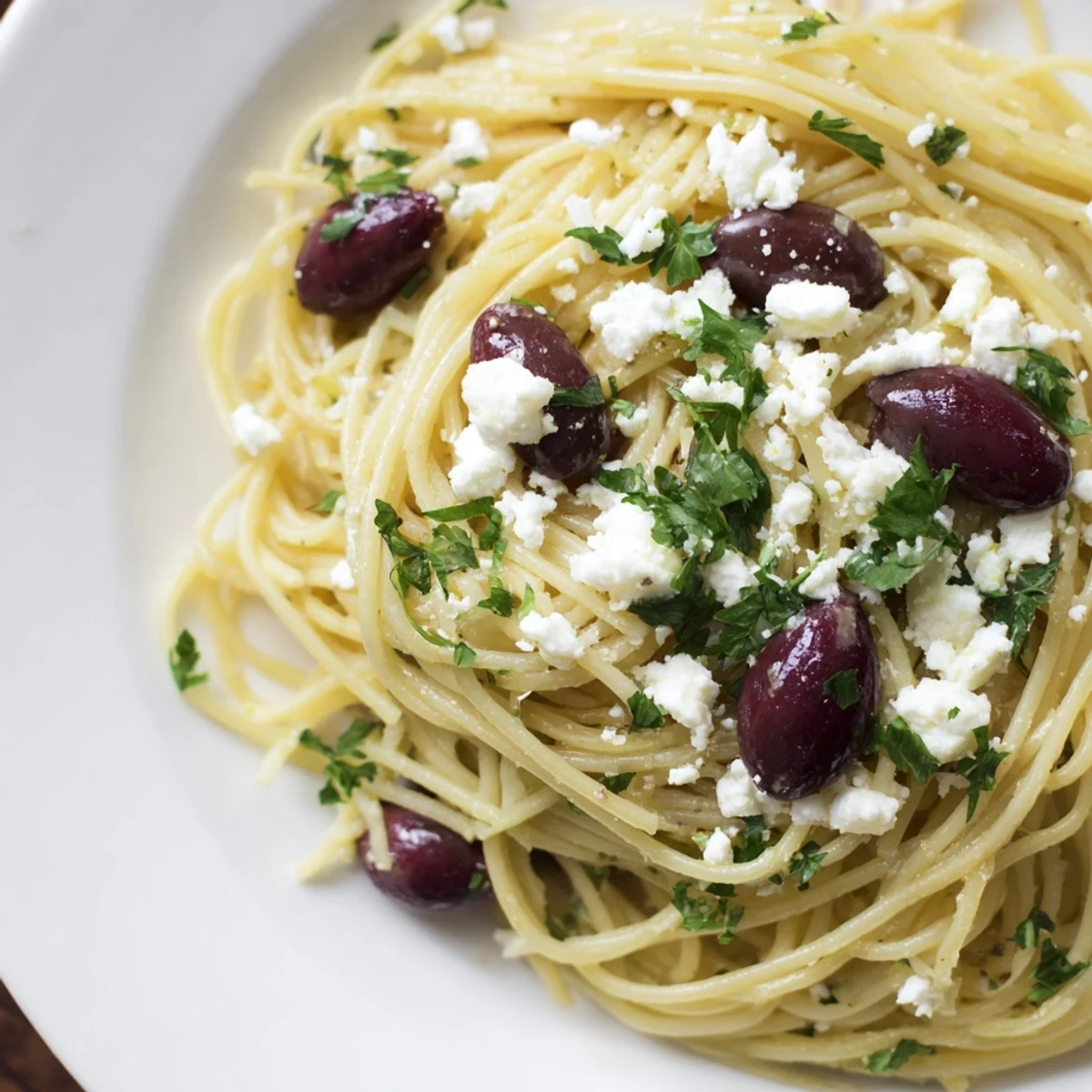 A generous serving of Greek Chicken Spaghetti on a dinner plate, garnished with feta and olives, ready to enjoy.