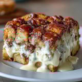 A rich slice of Cream Cheese Swirl Cinnamon Roll French Toast Bake served warm on a rustic plate.
