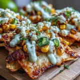 Vibrant Cinco de Mayo Elote Nachos loaded with cotija cheese, fresh cilantro, jalapeño, and zesty lime wedges for a festive appetizer.  