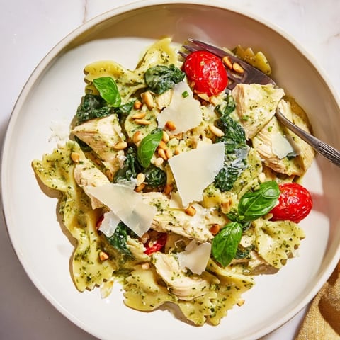 Creamy pesto chicken bowtie pasta topped with fresh basil and toasted pine nuts.  