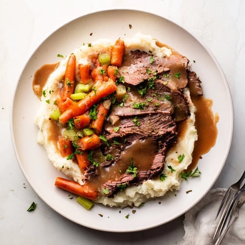 Slow Cooker Pot Roast served with creamy mashed potatoes and fresh parsley garnish.  