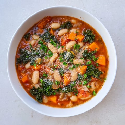 A steaming bowl of Italian Bean & Kale Stew, showcasing rustic textures and vibrant greens.