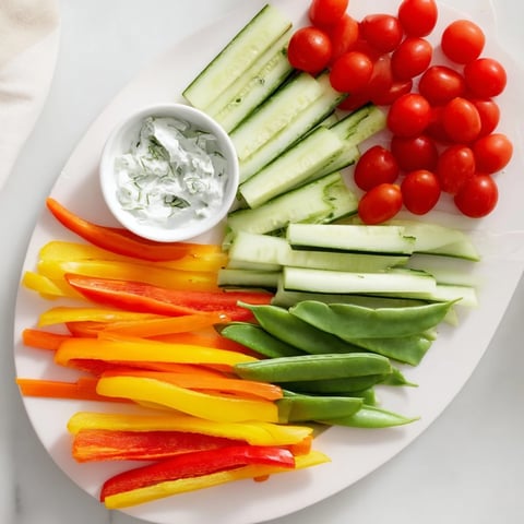 A colorful Veggie Platter showcasing fan-shaped cucumber and carrot slices with creamy herbed dip.