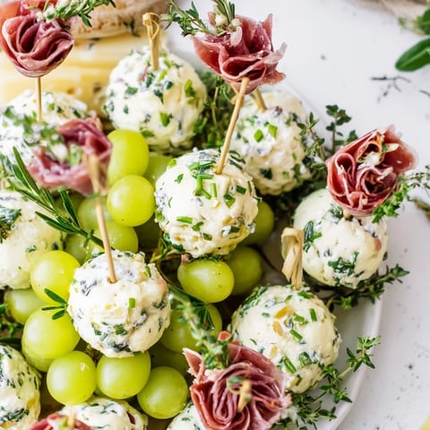 Festive Mistletoe Kissing Ball appetizer with creamy cheese, vibrant grapes, and savory prosciutto.