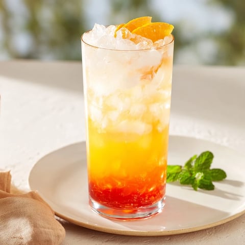Layered Alpine Sunrise mocktail, a beautiful drink with orange and red sunrise hues.
