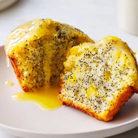 Warm, golden Lemon Poppy Seed Muffins cooling on a rack, sprinkled with a sweet lemon glaze.