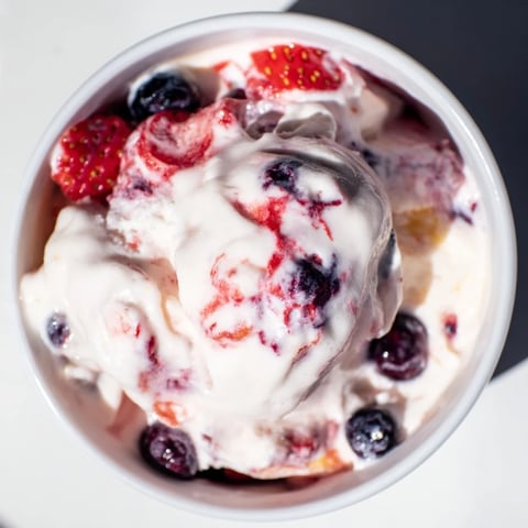 A close-up of creamy cottage cheese ice cream swirled with frozen berries, a delicious, healthy dessert.