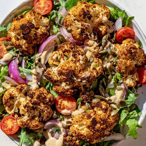 Golden, air-fried Crispy Cauliflower Salad sits atop fresh greens, drizzled with creamy tahini dressing.