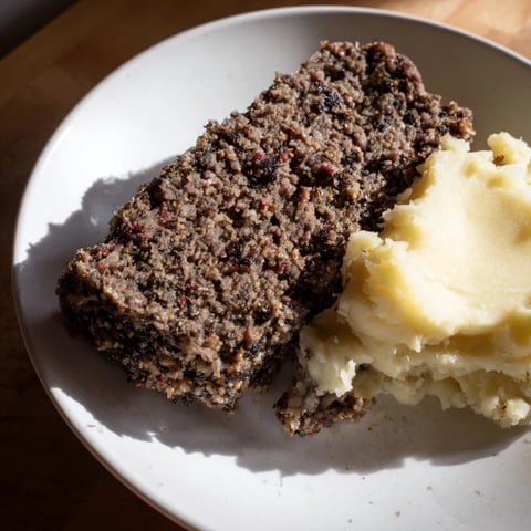 A steaming plate of Scottish haggis, richly spiced and served with creamy mashed neeps and tatties.
