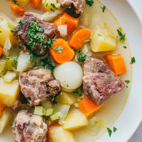 Steaming bowl of Welsh Cawl stew, showcasing tender lamb and root vegetables simmering in broth.