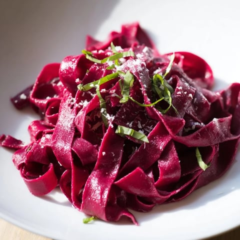 Vibrant magenta Beet Noodle Pasta, perfectly twirled and ready to be tossed with herbs and cheese.