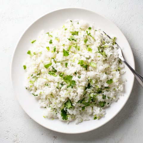 Fluffy long-grain rice mixed with chopped cilantro and lime zest, served warm as a vibrant Mexican side dish.