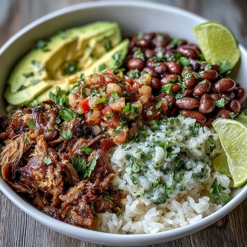 Fork-tender slow-cooked carnitas are piled high over fluffy white rice in this hearty gluten-free bowl, garnished with creamy avocado and cilantro.