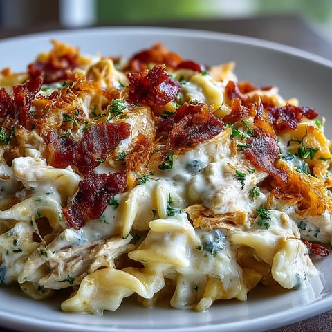 Creamy Jalapeño Popper Chicken Pasta served in a skillet with melted cheddar, crispy bacon, and fresh jalapeño slices.