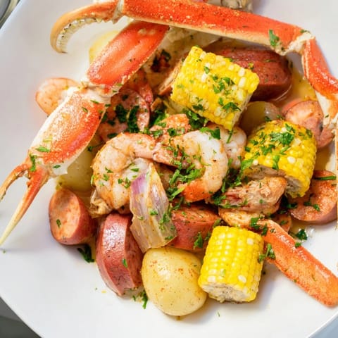 Festive seafood boil with crab legs, shrimp, and sausage, served with fresh lemon.  