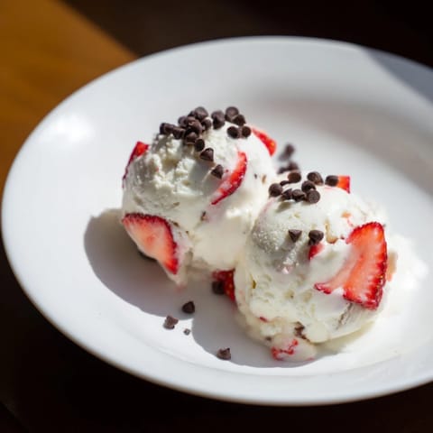 A close-up of thick, homemade cottage cheese ice cream, swirled with chunks of fresh berries.