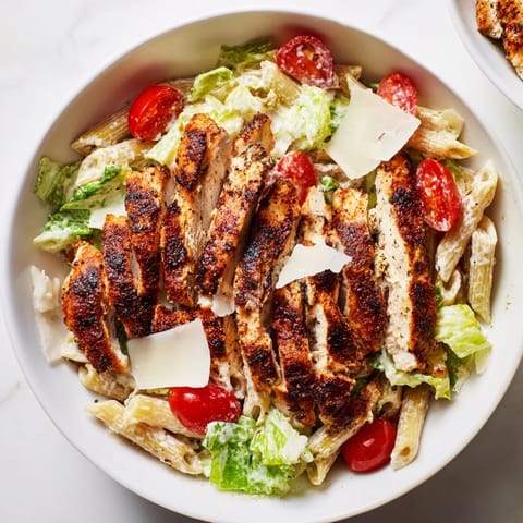 A rustic serving of Spicy Chicken Caesar Pasta topped with shaved Parmesan, crunchy croutons, and fresh parsley garnish.