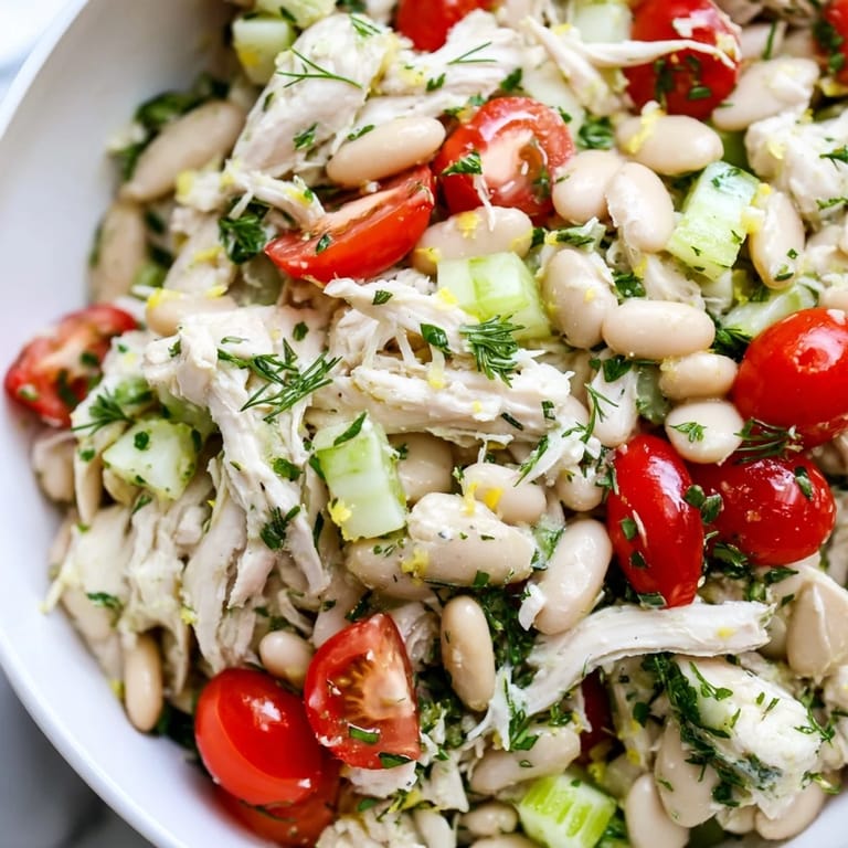Serving suggestion for Lemony White Bean Chicken Salad on a bed of greens with crusty bread for a summer meal.