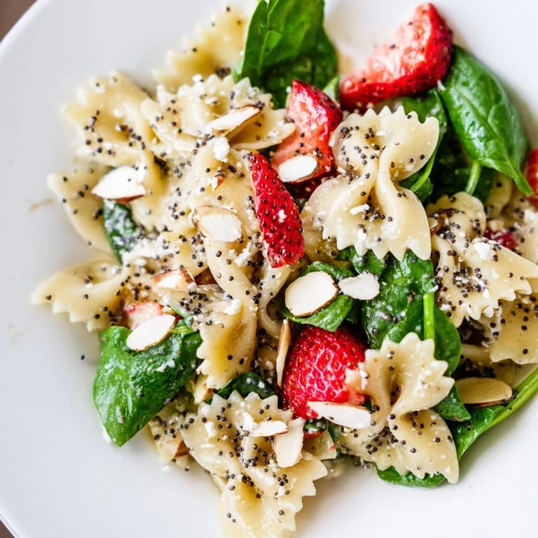 Colorful Spring Spinach Strawberry Pasta Salad bowl, perfect for summer picnics and served alongside a chilled glass of rosé wine.