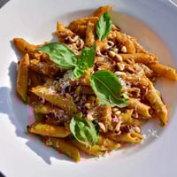 Creamy sun-dried tomato pesto pasta, glistening and ready to devour with fresh basil garnish.